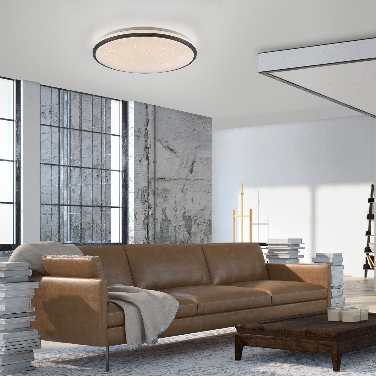 Mise en ambiance dans un salon, plafonnier rond allumé au plafond au-dessus d'un canapé.