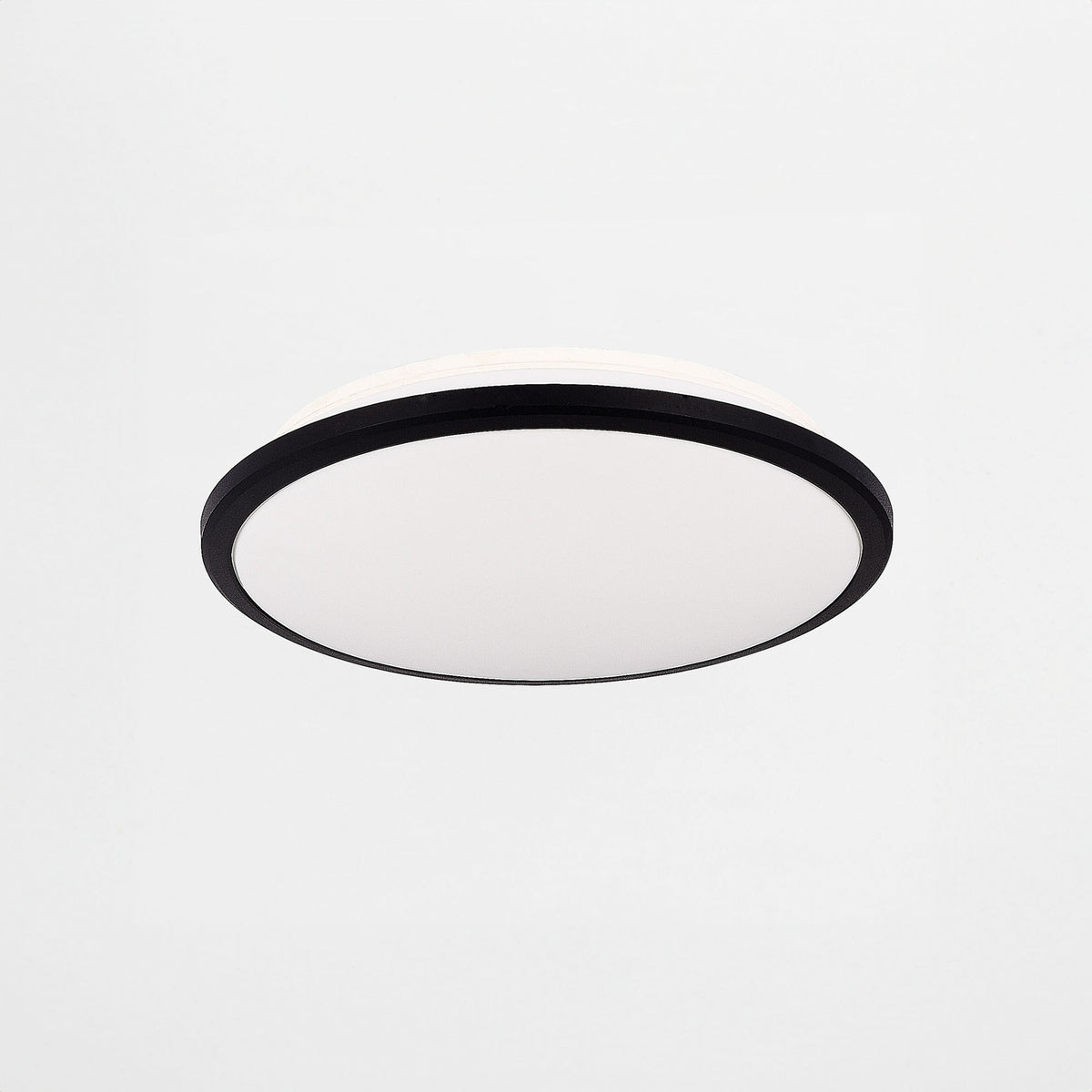 Plafonnier rond vu de trois quarts, cerclage noir fin et diffuseur opalin blanc bombé.