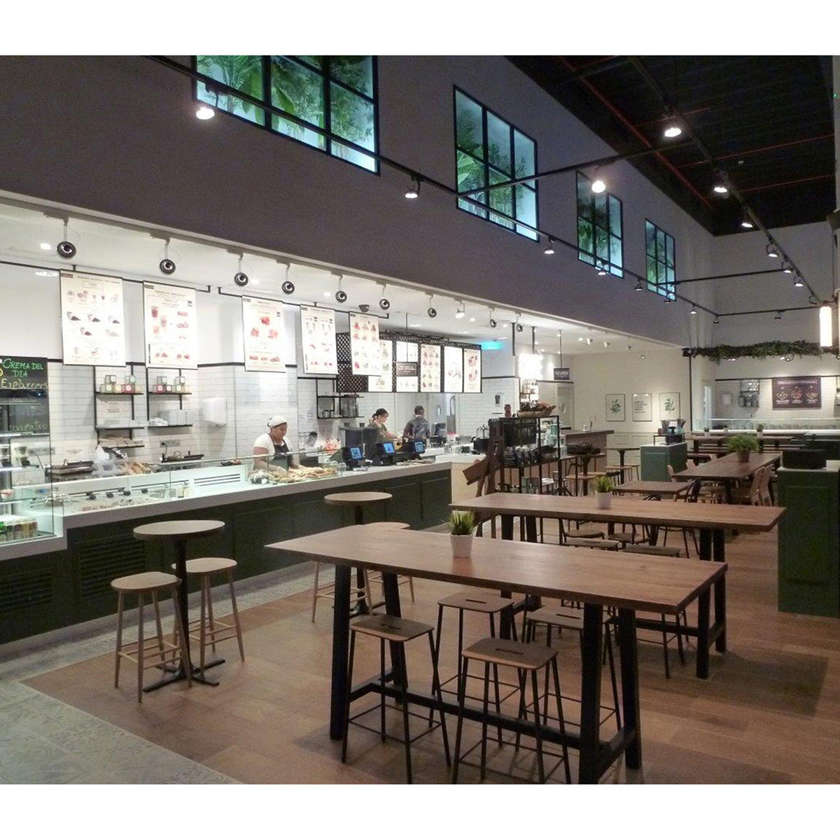 Intérieur de café avec rail de petits spots orientables éclairant le comptoir et les tables.