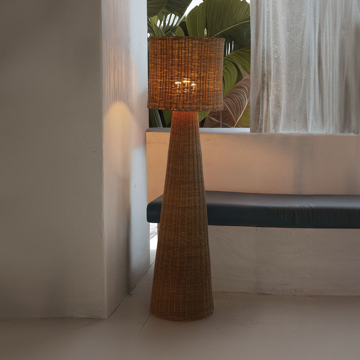 Lampadaire en fibres tressées posé au sol devant une fenêtre, intérieur clair