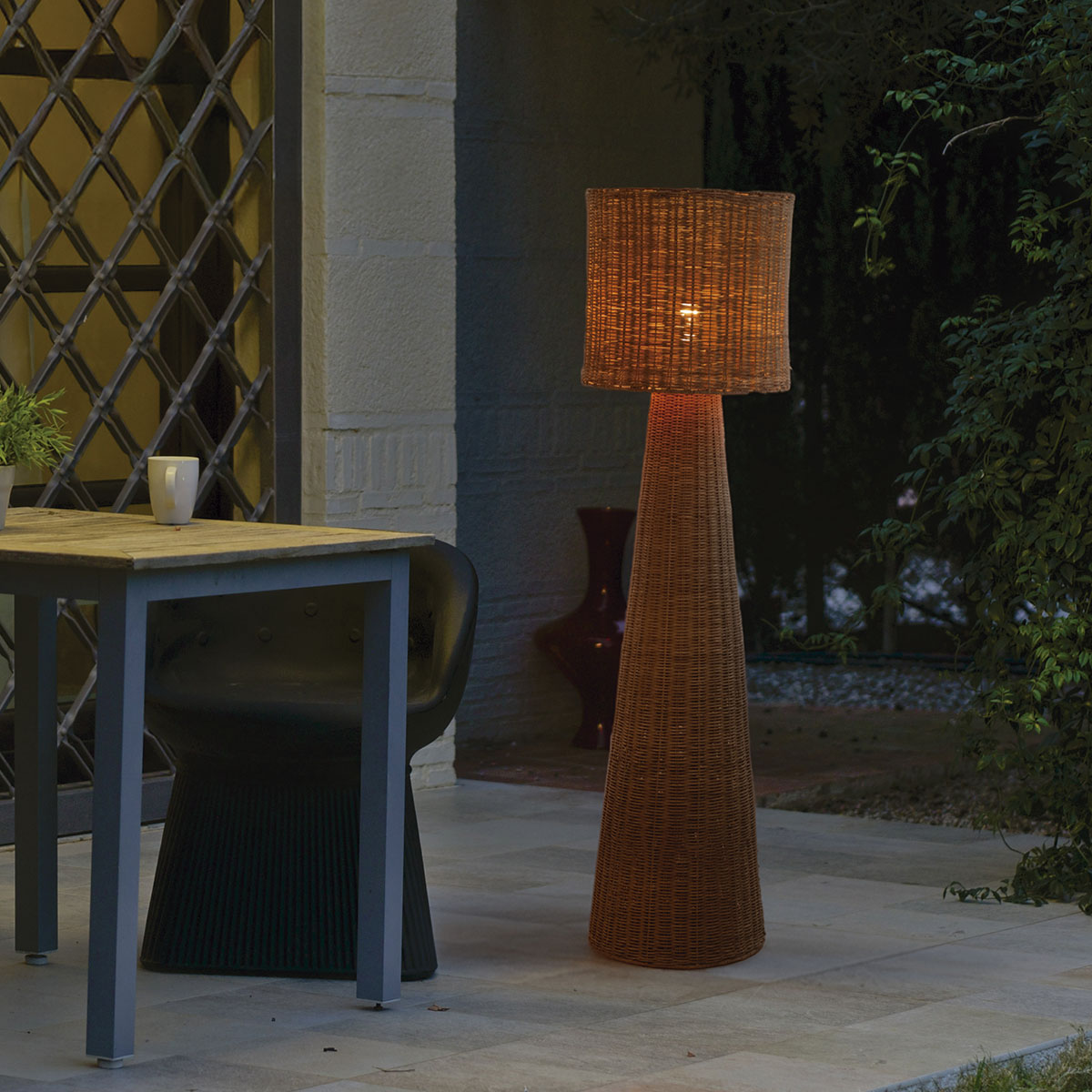 Lampadaire allumé sur une terrasse le soir, près d'une table et de chaises