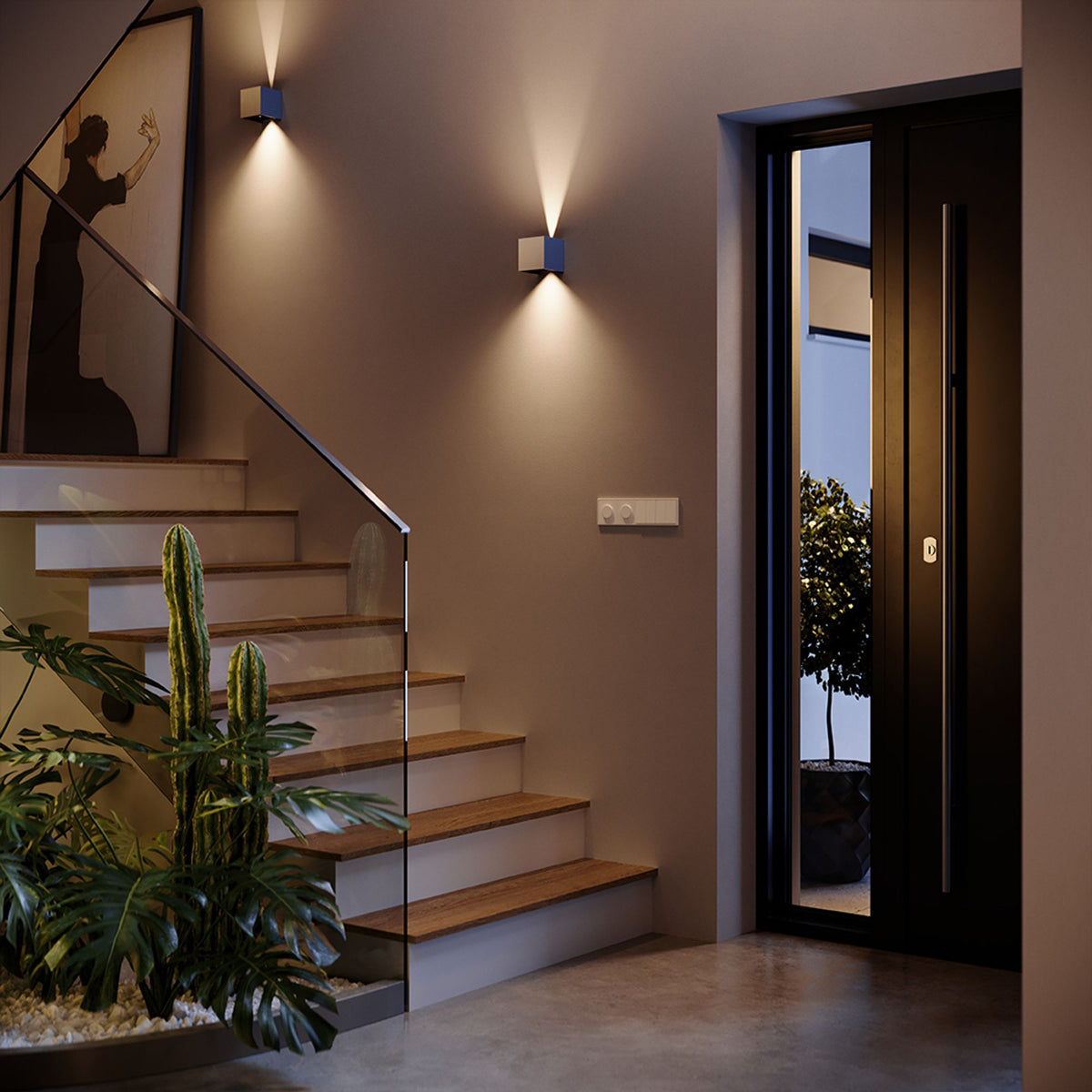 Entrée moderne avec applique murale allumée au-dessus d'un escalier en bois et plantes.