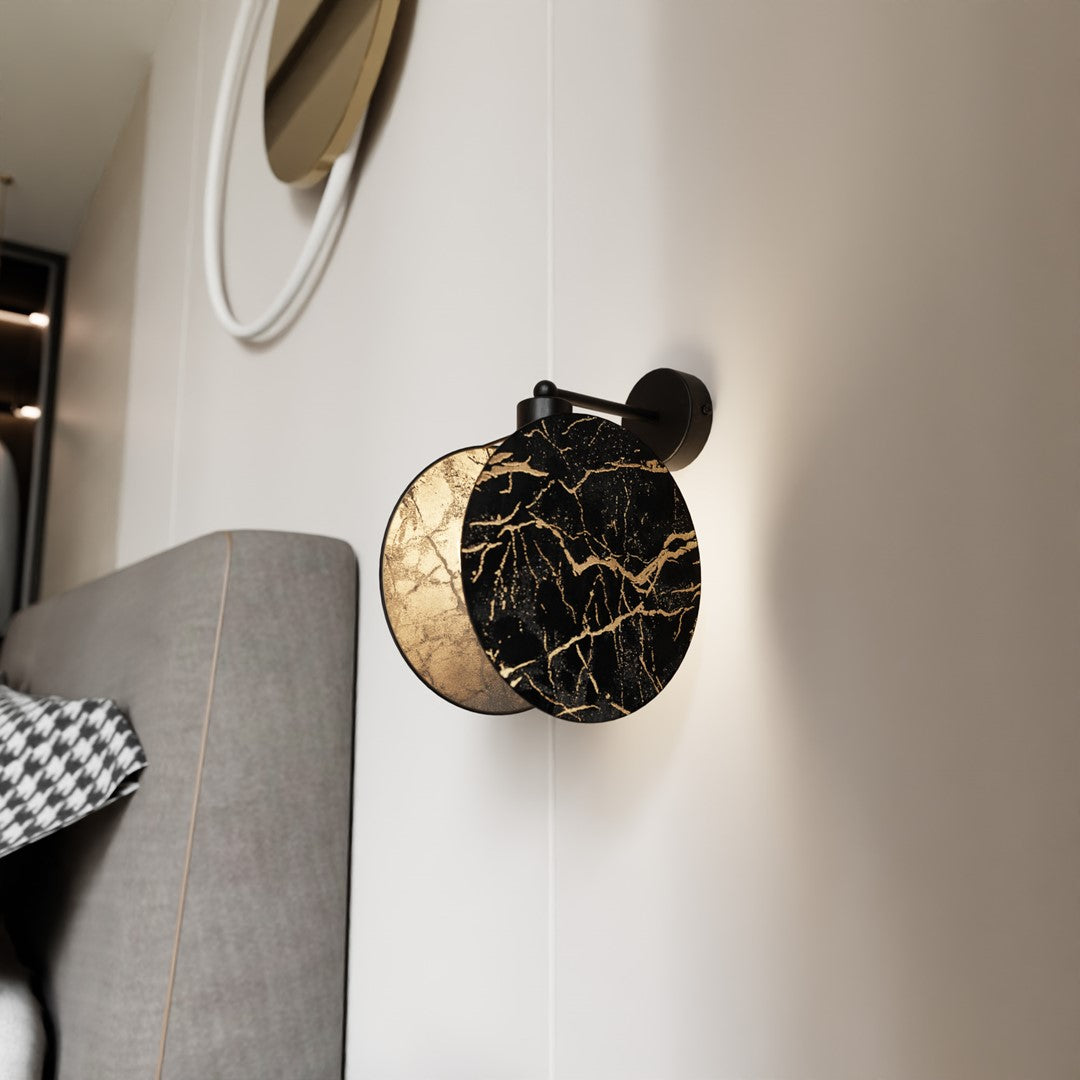 Vue rapprochée sur mur blanc, applique noire et dorée près d'un miroir rond.