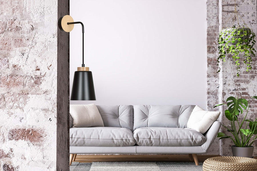 Mise en ambiance salon avec canapé gris, applique murale suspendue au-dessus du dossier.