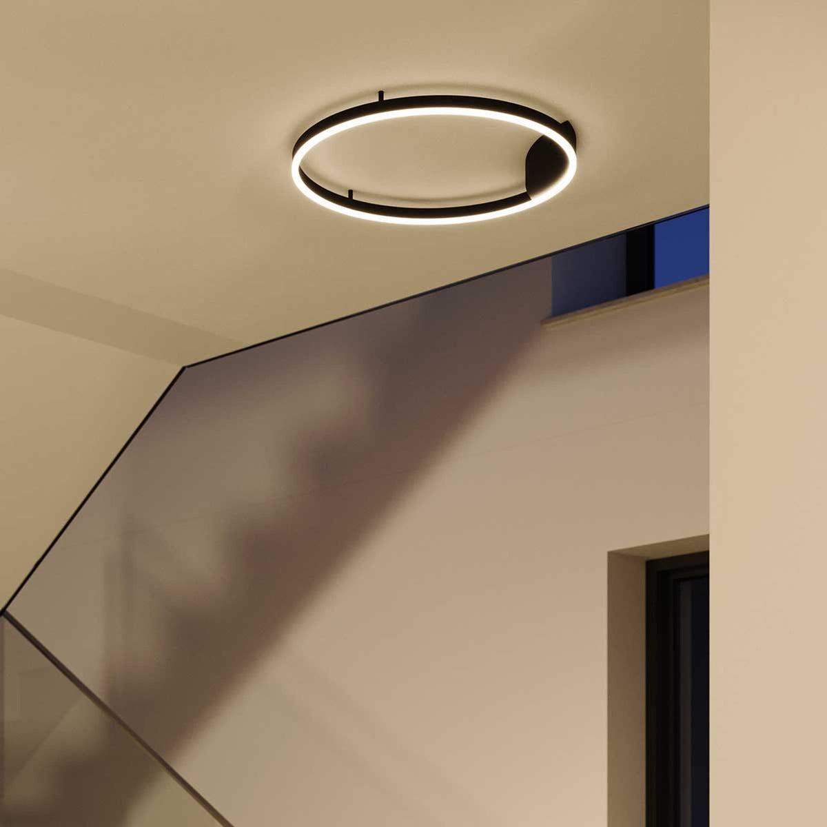 Luminaire anneau LED noir fixé au plafond dans une pièce