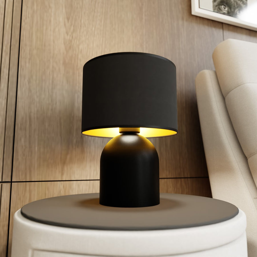 Lampe allumée posée sur table d'appoint, près canapé et tête de lit en bois.