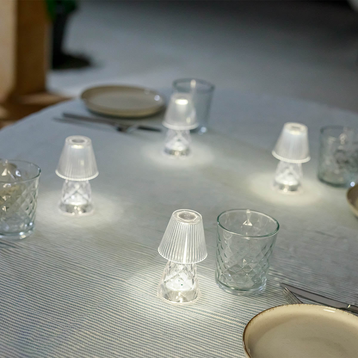 Lampes sans fil éclairant une table dressée avec assiettes et verres en verre
