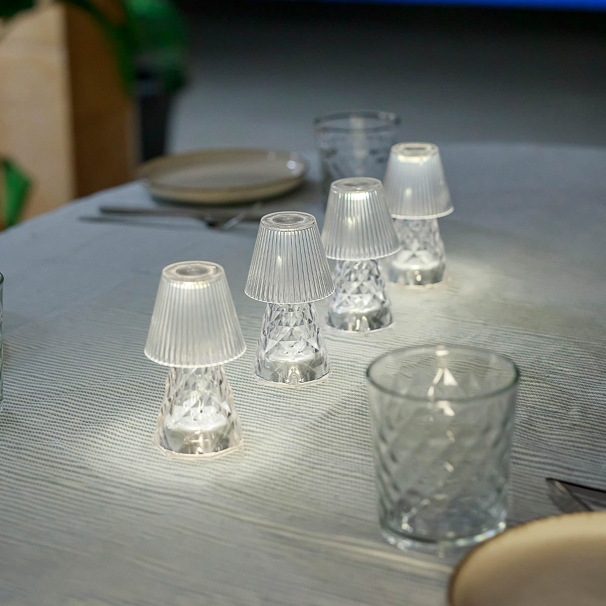 Gros plan sur plusieurs luminaires transparents allumés sur une nappe à rayures