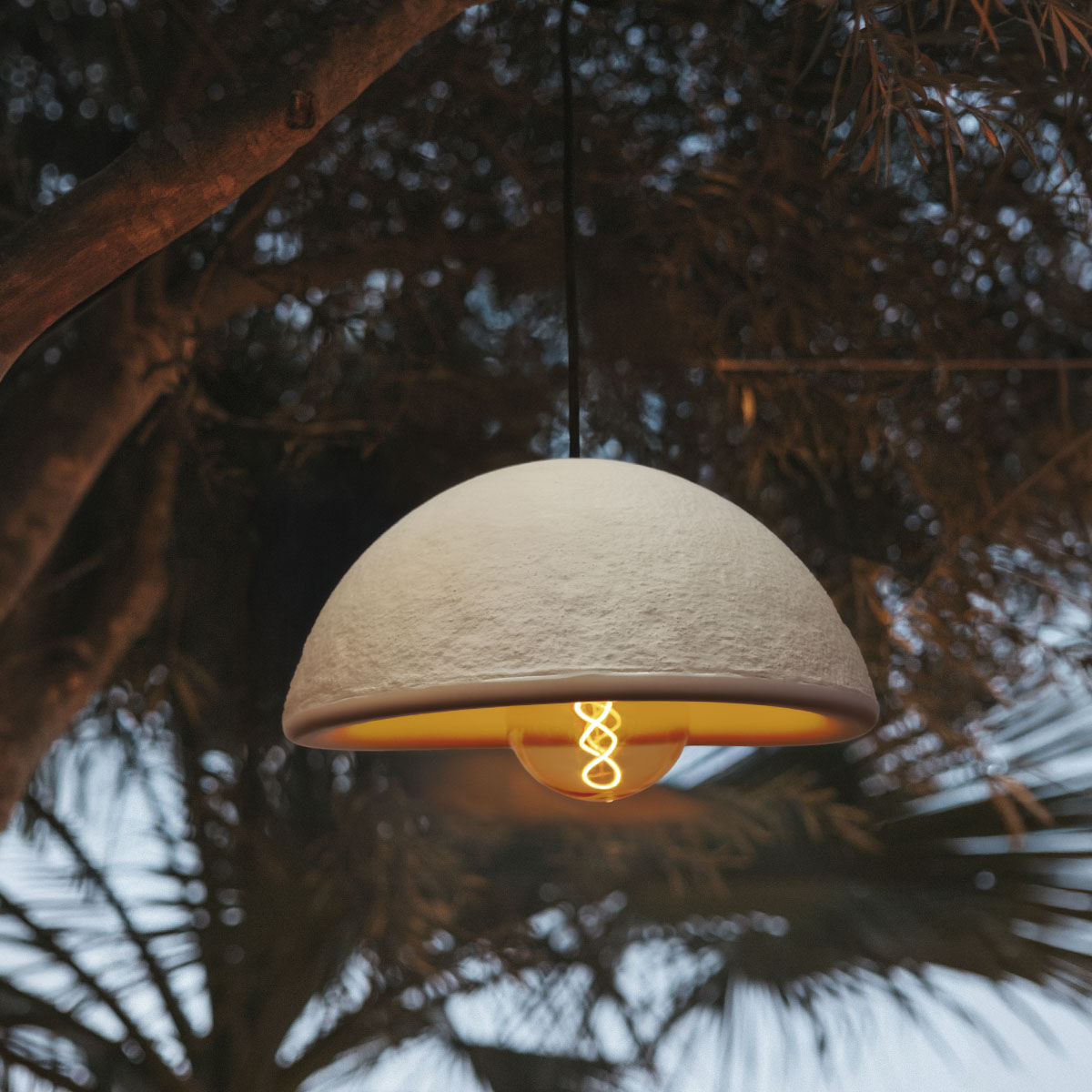 Luminaire blanc suspendu dans un arbre sombre, lumière chaude contrastant avec le feuillage nocturne.