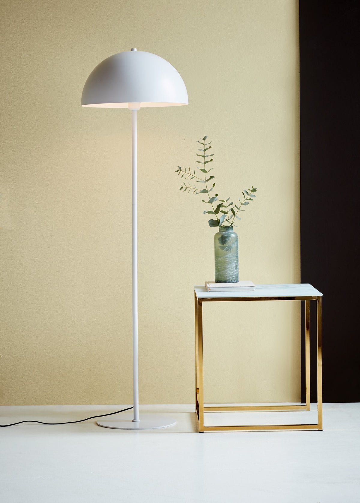 Mise en ambiance : lampadaire blanc allumé près d'une table dorée et d'un vase