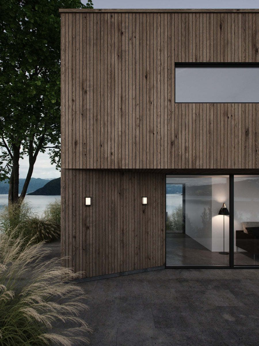 Vue extérieure d'une maison en bois avec deux appliques murales près d'un lac.