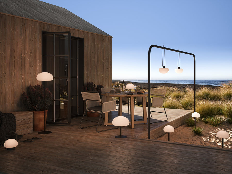 Scène de vie en terrasse face à la mer, plusieurs lampes nomades posées et suspendues.