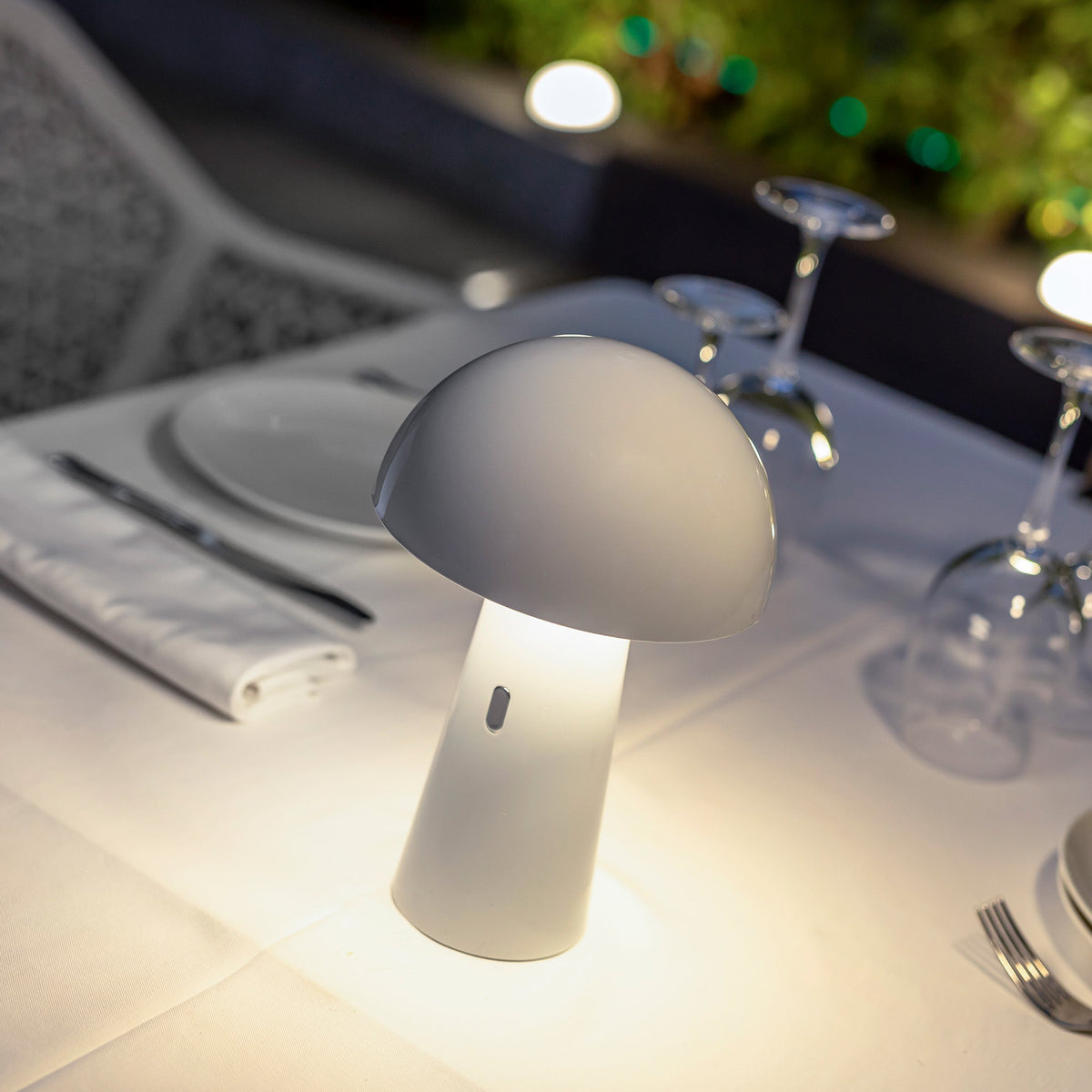 Lampe blanche allumée sur nappe blanche, mise en ambiance de restaurant le soir