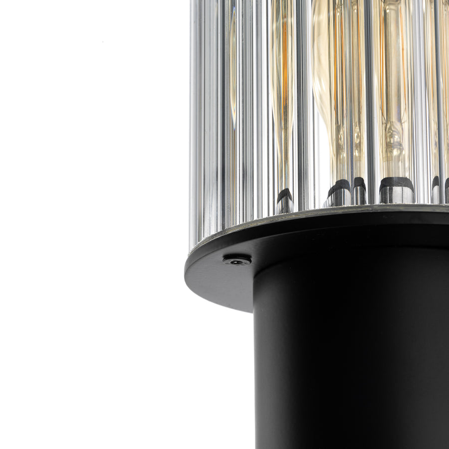 Gros plan sur le diffuseur en verre strié et la bague métallique noire retenant l'ampoule.