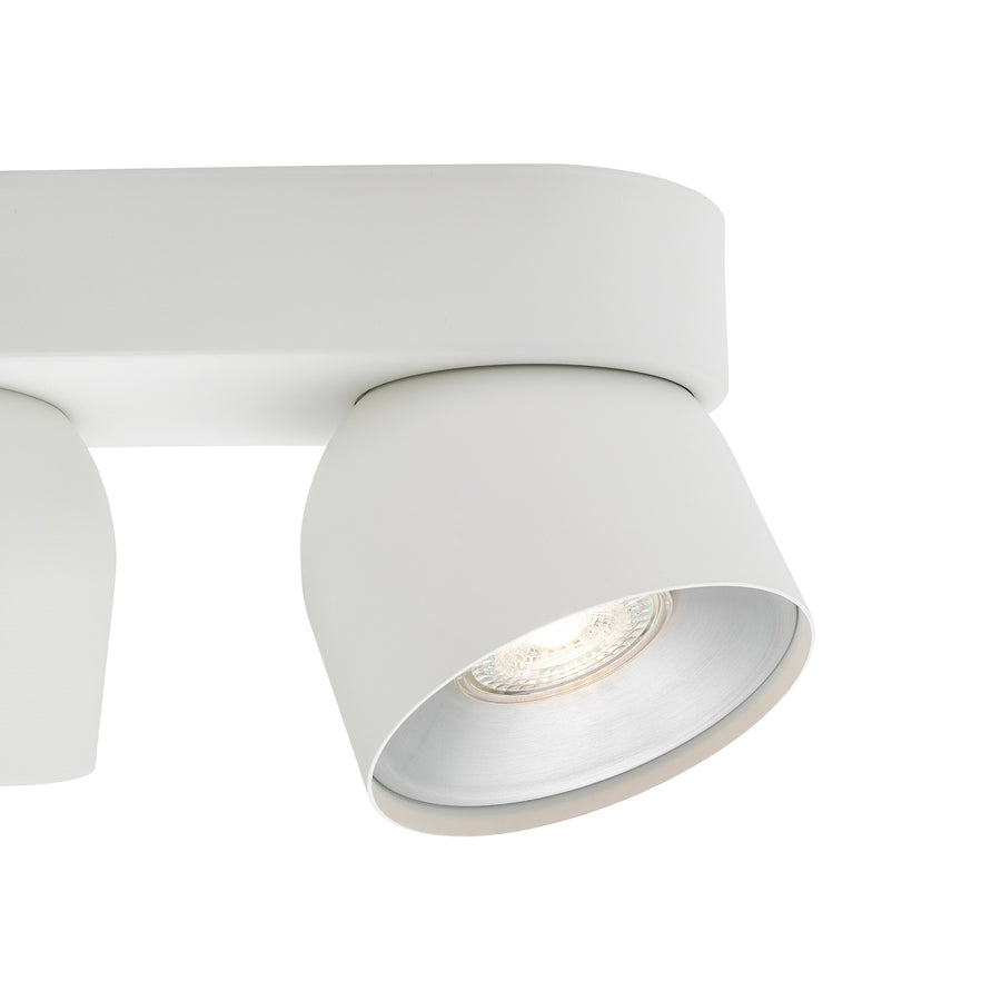 Détail rapproché d'un spot blanc incliné, réflecteur argenté et ampoule LED visible