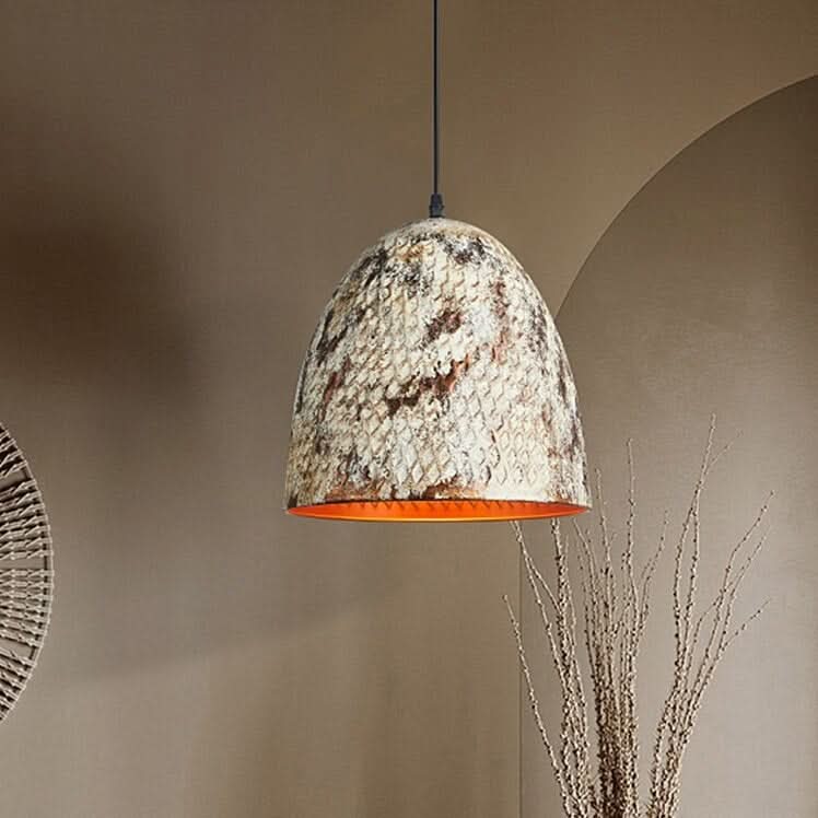 Luminaire suspendu devant un mur beige, décor en rotin et branches séchées