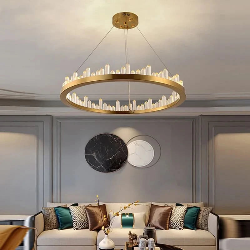 Version circulaire dorée du luminaire, cristaux dressés sur le pourtour, devant un canapé beige.