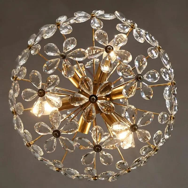 Vue rapprochée du globe floral en cristal, armature dorée et ampoules visibles au centre.