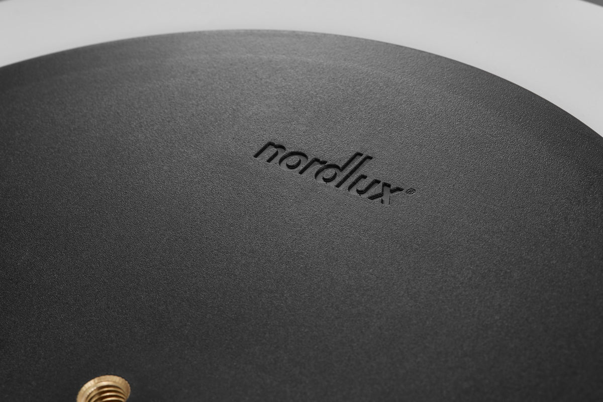 Gros plan sur le dessous noir mat avec filetage doré et logo en relief.