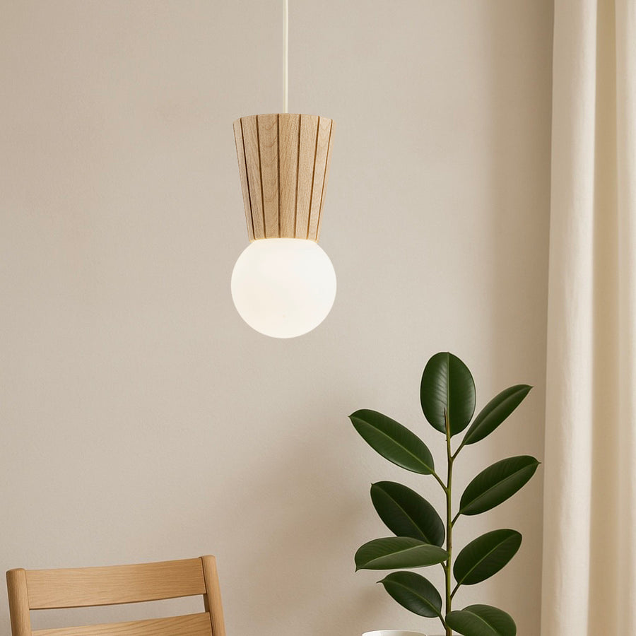 Mise en situation du luminaire près d'une plante verte et d'une chaise.