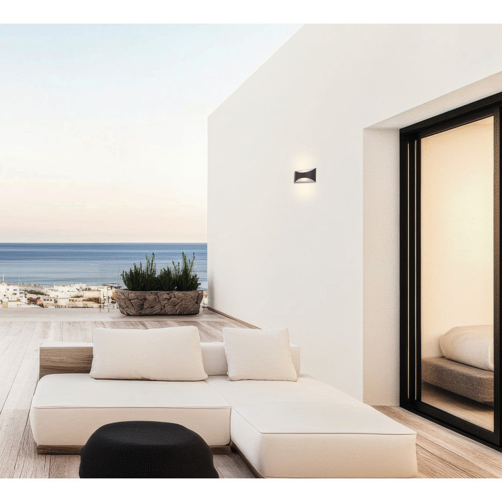 Mise en ambiance sur terrasse, applique murale éclairant un mur blanc près de l'océan.