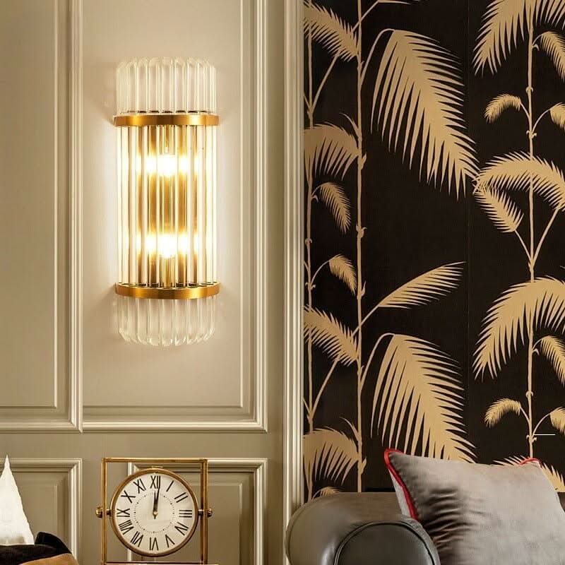 Applique murale dorée allumée sur mur mouluré, à côté d'un papier peint floral noir et doré.