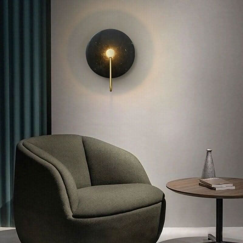 Applique noire dans un salon, fauteuil vert et table d'appoint en bois