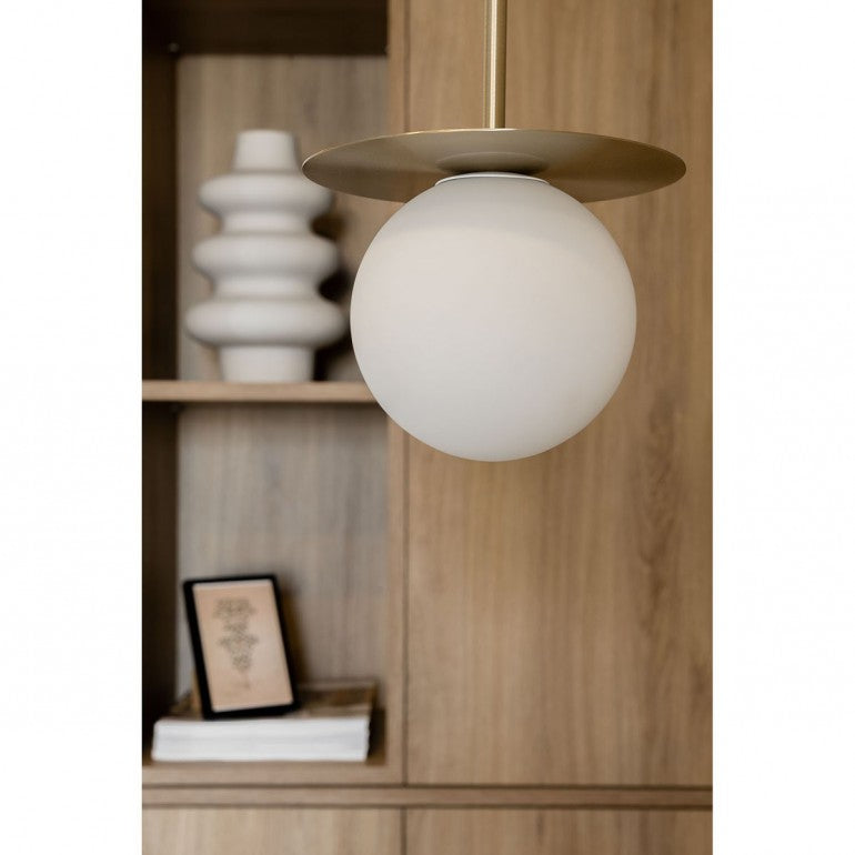 Gros plan sur un globe blanc et sa coupelle dorée, dans une bibliothèque en bois.