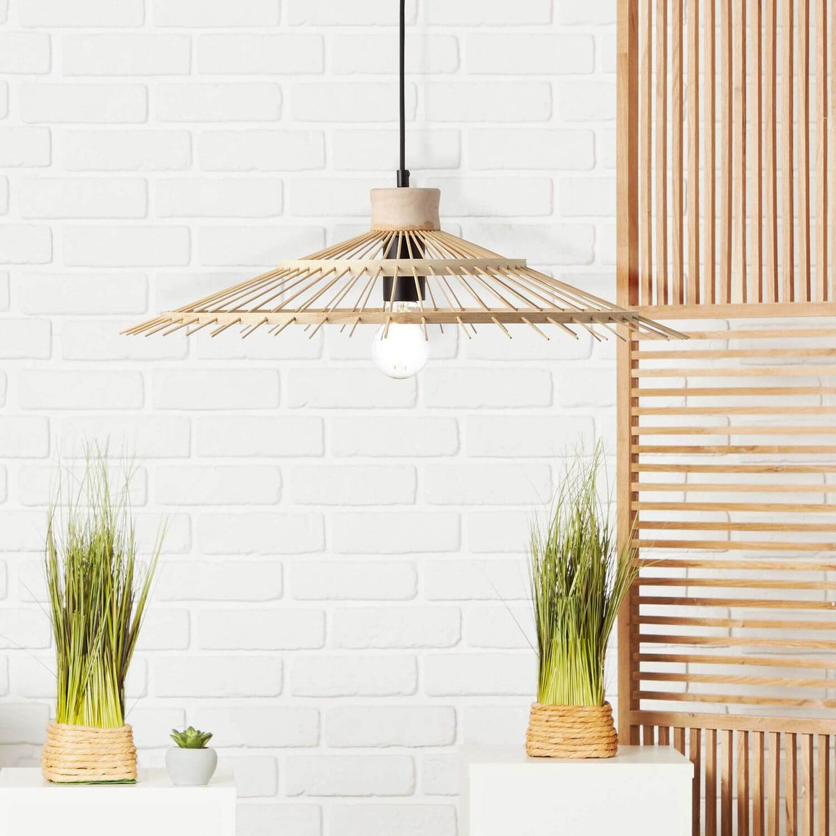 Mise en ambiance : suspension bambou devant un mur de briques blanches et un paravent