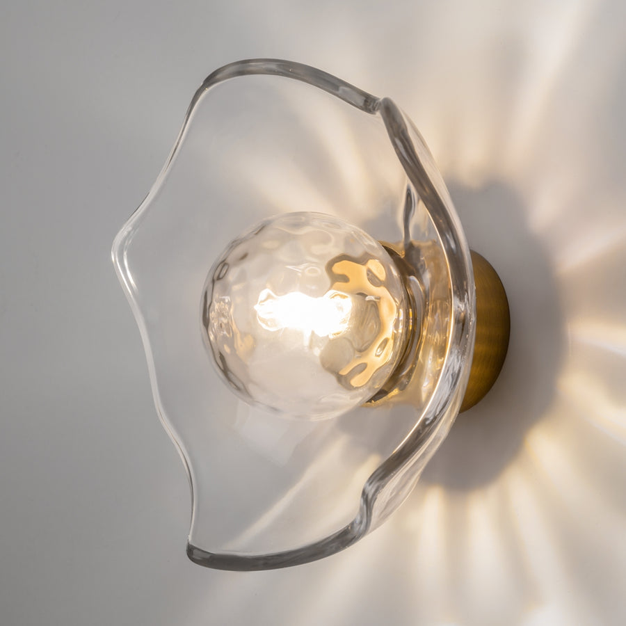 Applique allumée fixée au mur, halo lumineux rayonnant projeté autour du verre.
