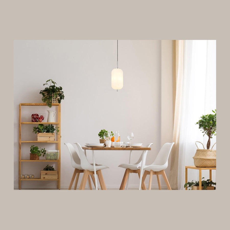 Suspension allumée au-dessus d'une table à manger dans un intérieur clair et végétal