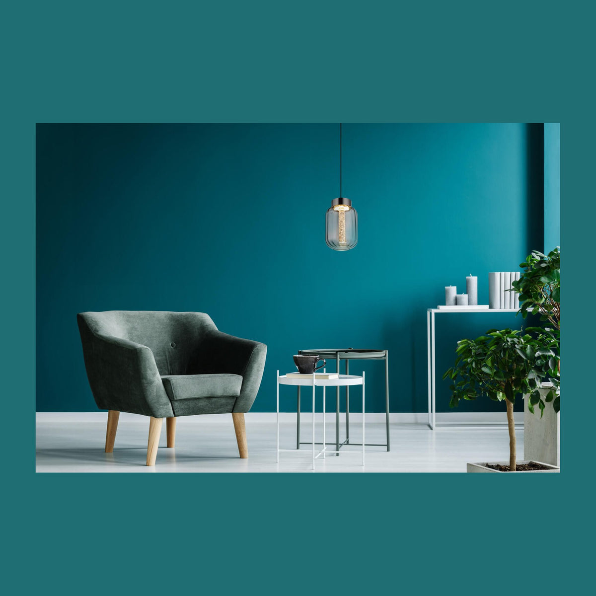 Mise en ambiance d'un intérieur bleu canard avec fauteuil en velours et suspension allumée