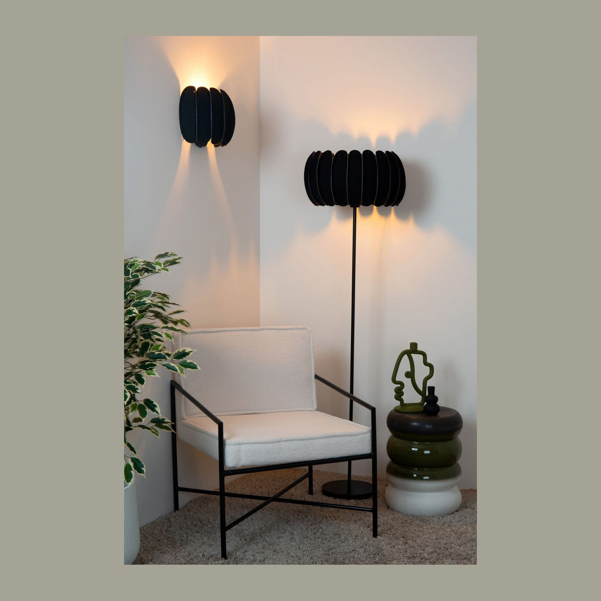 Vue d'ensemble d'un coin salon avec applique murale noire allumée et lampadaire assorti.