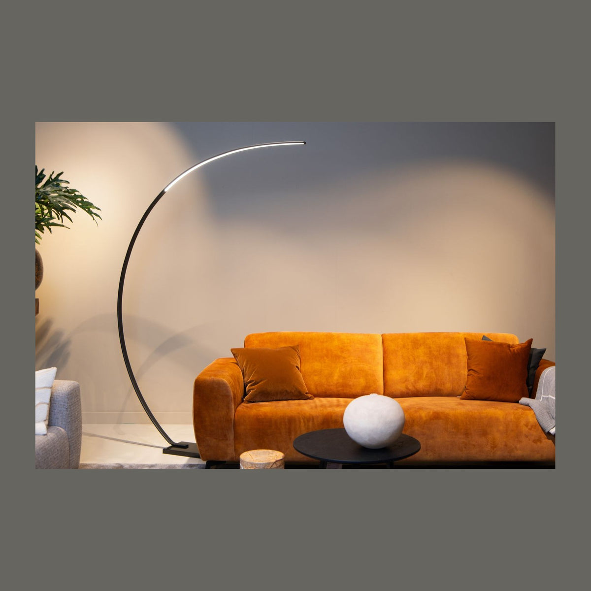 Lampadaire arc noir en situation, éclairant un canapé orange dans un salon