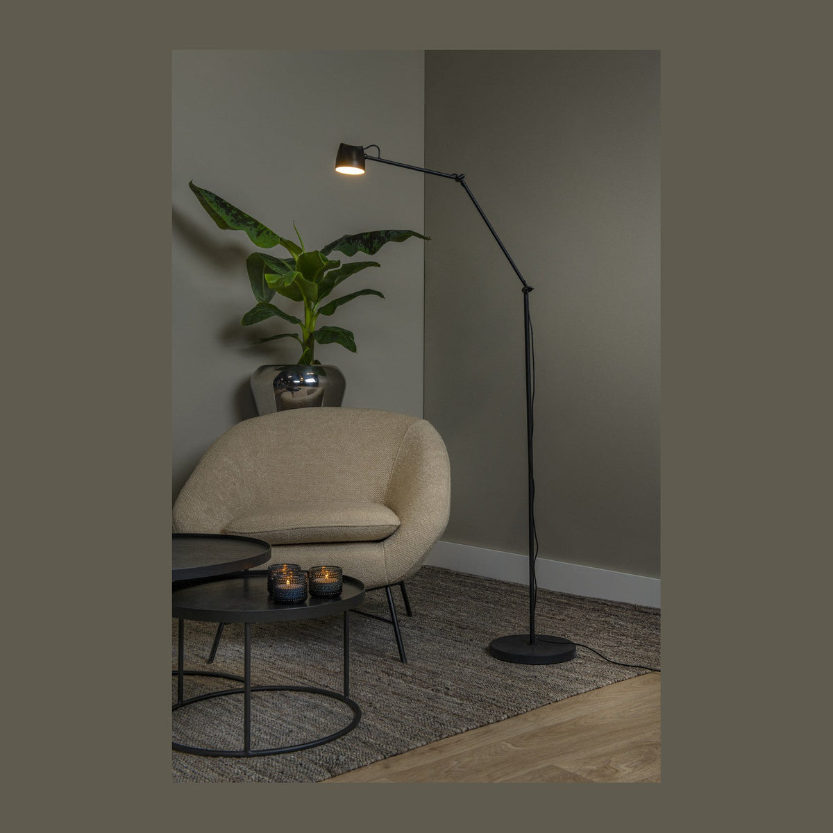 Lampadaire noir posé près d'un fauteuil beige dans un salon gris