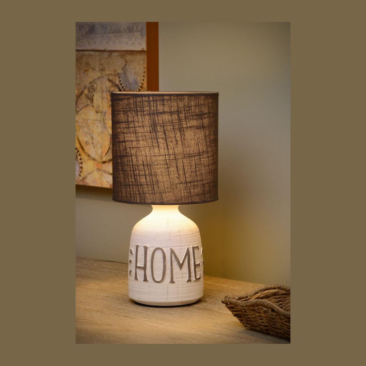 Lampe à poser allumée sur une table en bois avec panier.