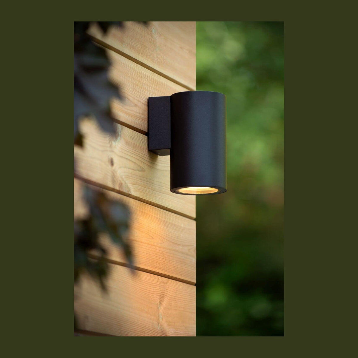 Applique extérieure noire fixée sur mur de bois, éclairage vers le bas, ambiance jardin