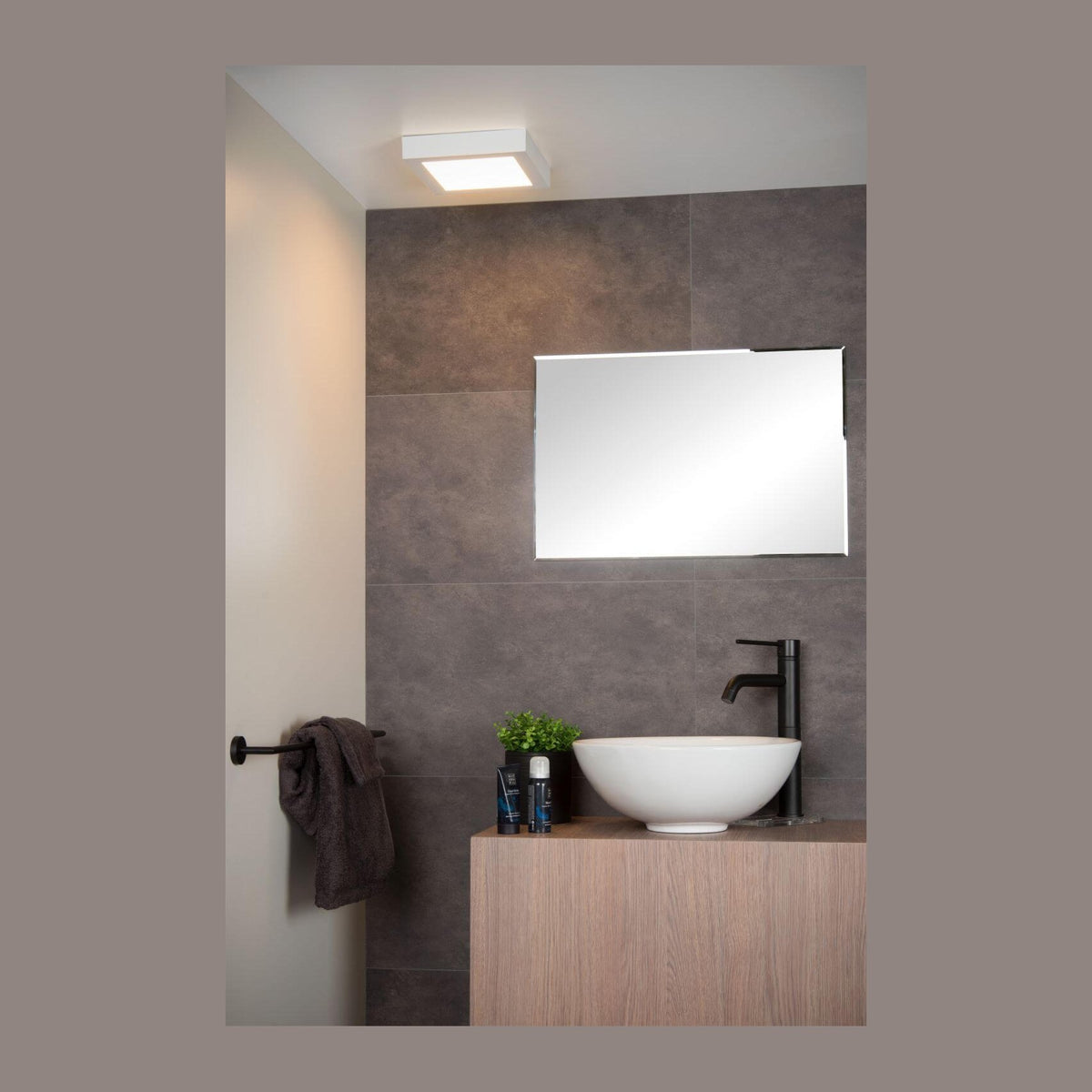 Salle de bain moderne, plafonnier carré blanc allumé au-dessus du miroir et de la vasque