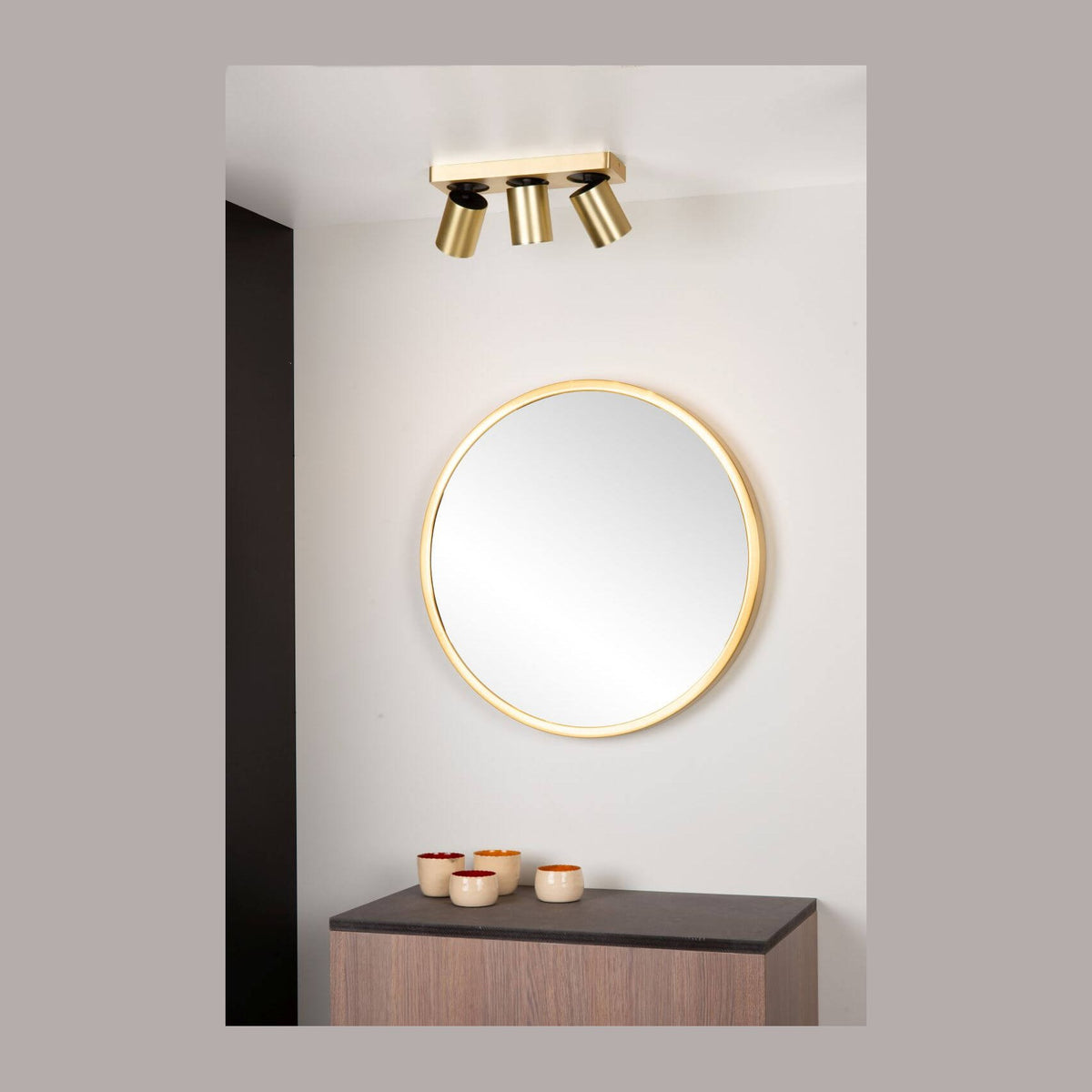 Plafonnier doré fixé au plafond au-dessus d'un miroir rond et d'un buffet en bois
