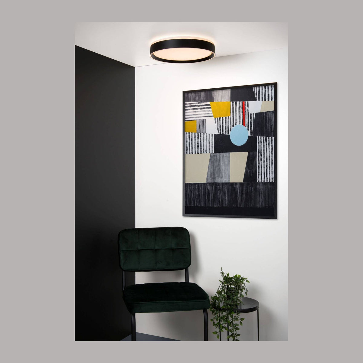 Luminaire rond fixé au plafond dans un salon décoré d'une toile abstraite colorée