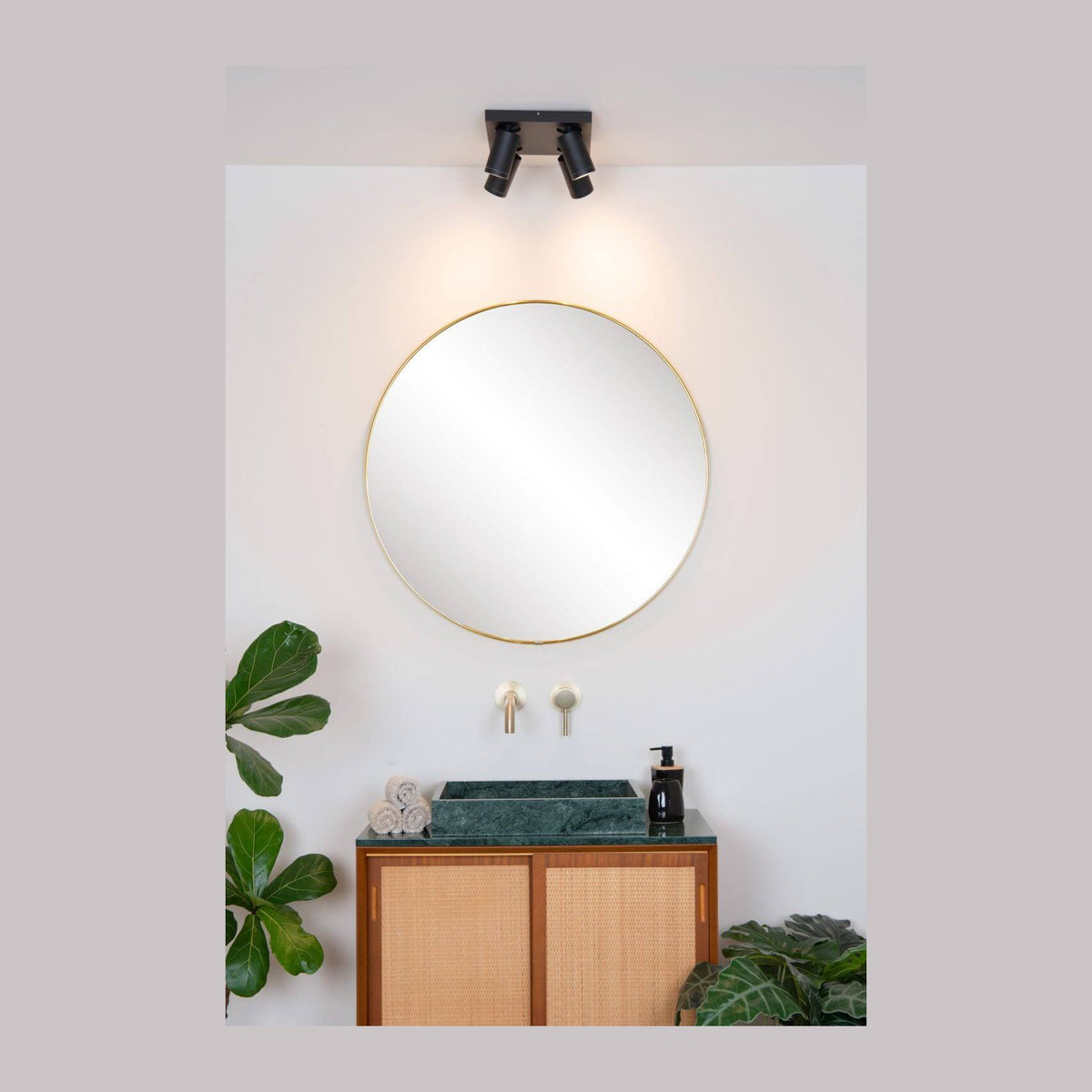 Vue d'ensemble de la salle de bain avec plafonnier noir allumé au-dessus du miroir rond.