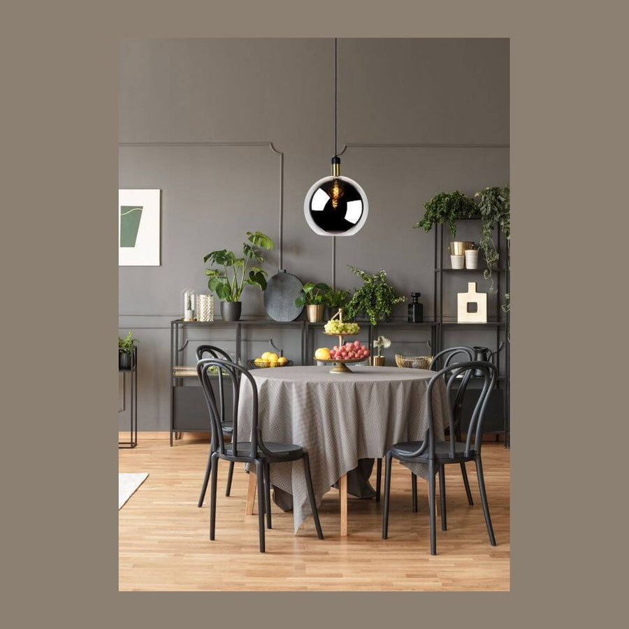 Suspension en verre fumé éclairée au-dessus d'une table ronde et de chaises noires.
