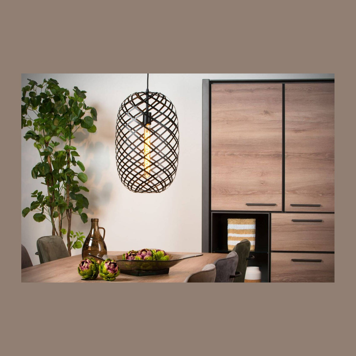 Suspension noire suspendue au-dessus d'une table en bois, décor avec artichauts et plante verte.