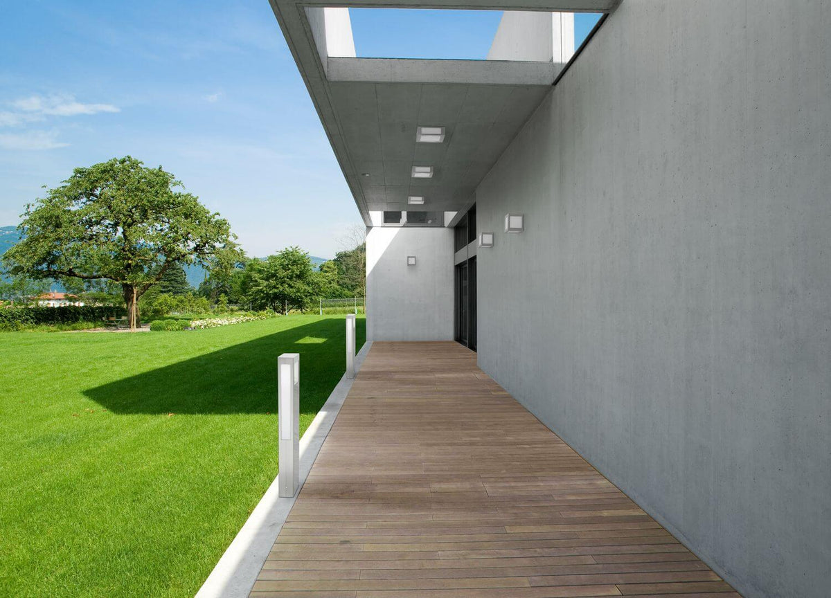 Mise en ambiance extérieure avec deux bornes lumineuses inox sur une terrasse en bois