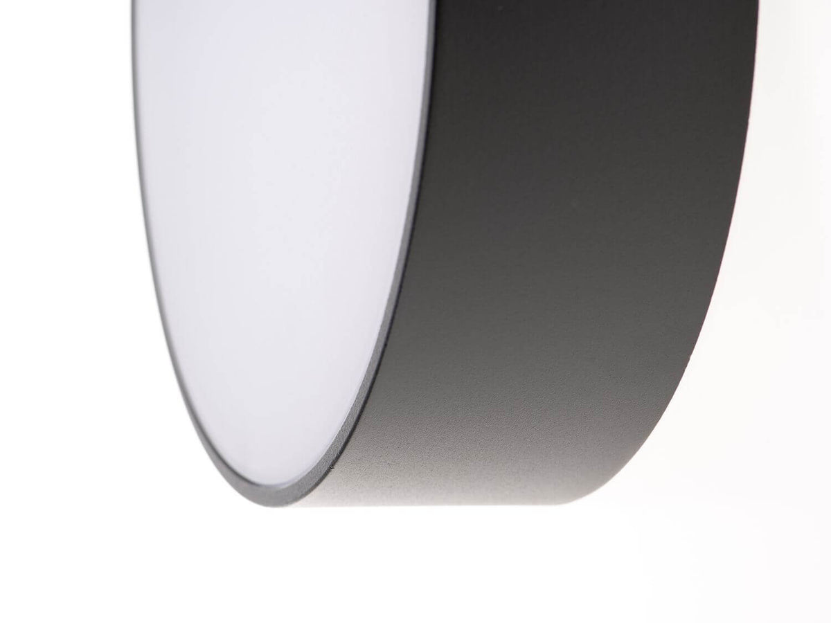 Gros plan sur le bord du luminaire montrant la finition granulée anthracite et le diffuseur blanc.