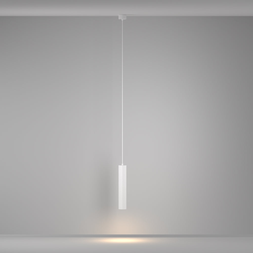 Mise en ambiance, le luminaire suspendu projette une lumière chaude sur un mur gris
