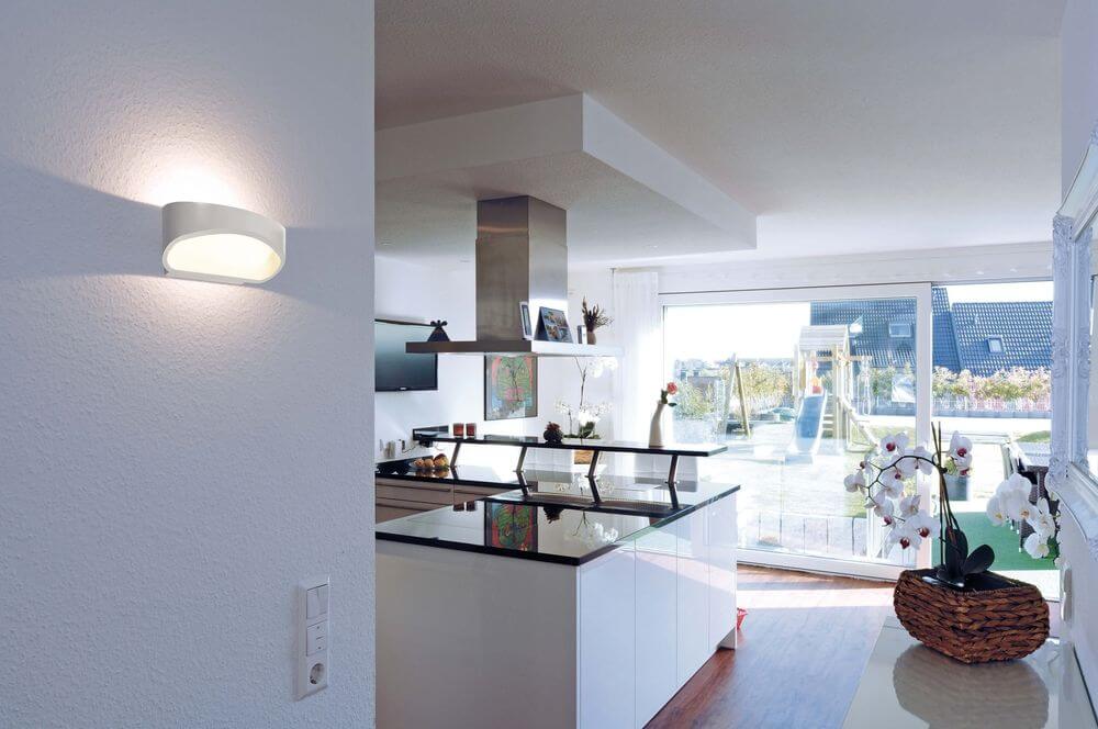 Applique blanche allumée sur un mur de cuisine, éclairage indirect dans la pièce.