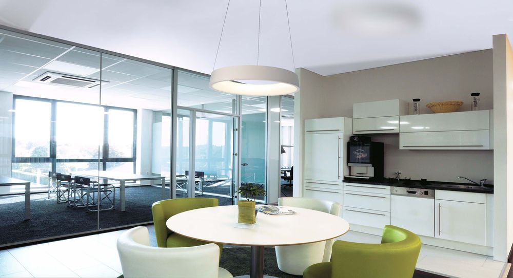 Mise en ambiance dans un bureau avec table blanche et chaises vertes