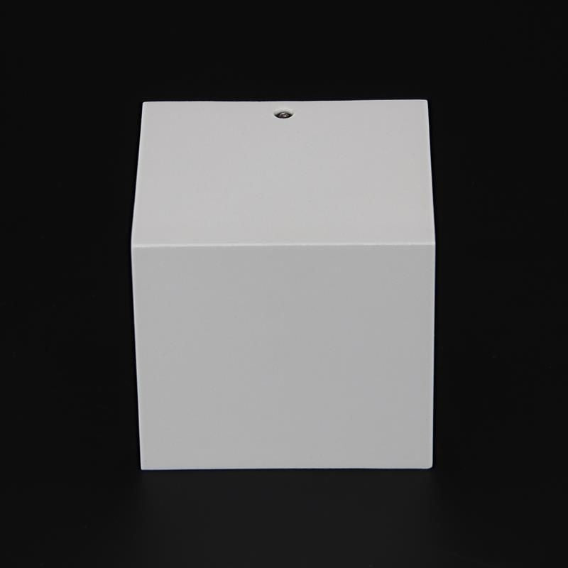 Vue frontale du boîtier cubique blanc avec vis de fixation apparente.