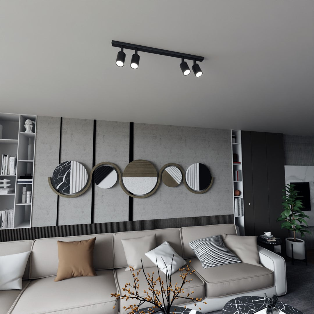Mise en ambiance dans un salon moderne, spot noir fixé au plafond au-dessus du canapé.
